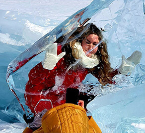 A girl takes a picture across the ice of Lake Baikal